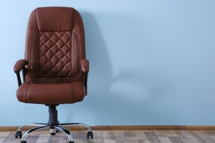 Ember ül ergonomikus irodai széken, fenntartva helyes testtartást és hátsó támaszt.