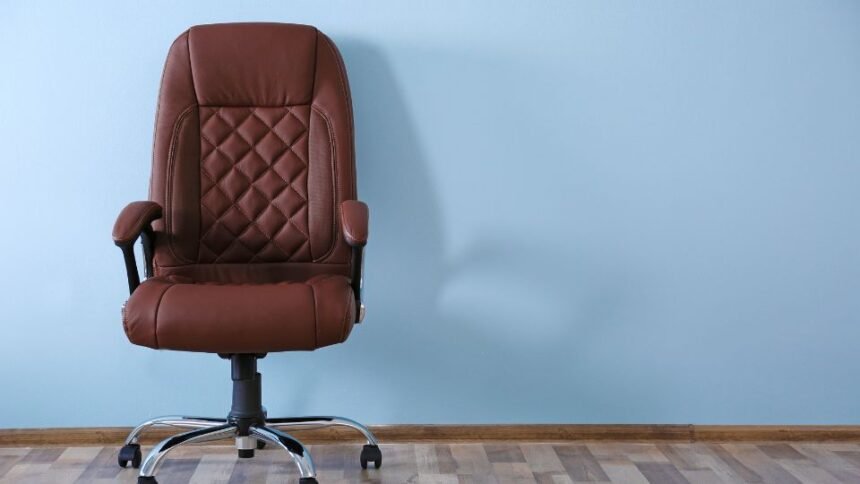 Ember ül ergonomikus irodai széken, fenntartva helyes testtartást és hátsó támaszt.